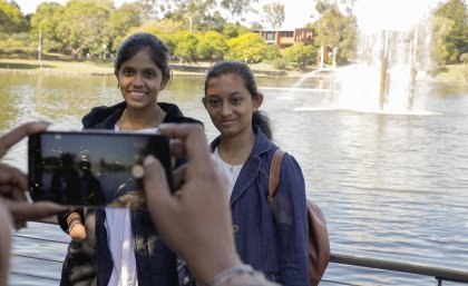 Harini (L) and Abinaya getting their photo taken in front of the UQ lakes.